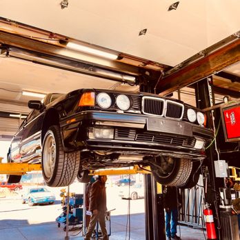 A black car raised on a lift in an auto repair shop